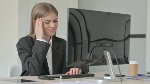 Young Businesswoman having Headache while Working on Desktop Computer