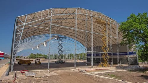 Attaching the roof and sides to a huge lattice framework building - construction site time lapse