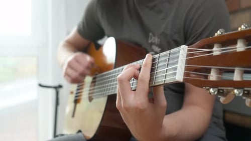 Manos de guitarrista tocando acordes de barra en una guitarra Clásica de cuerdas de nylon