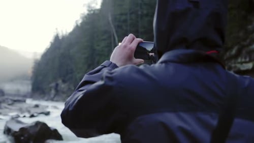 Person Filming Mountain River with Mobile Phone