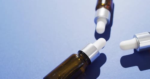 Close up of dropper serum bottles on blue background with copy space