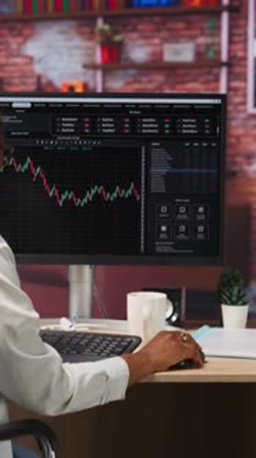 Analyst Manages Financial Data on Computer at Desk