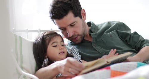 Father and Daughter Reading a Book in Bed