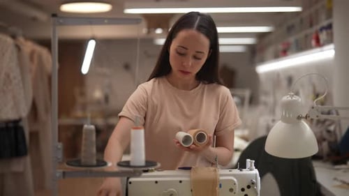 Woman Inspecting Thread Spools in Sewing Studio
