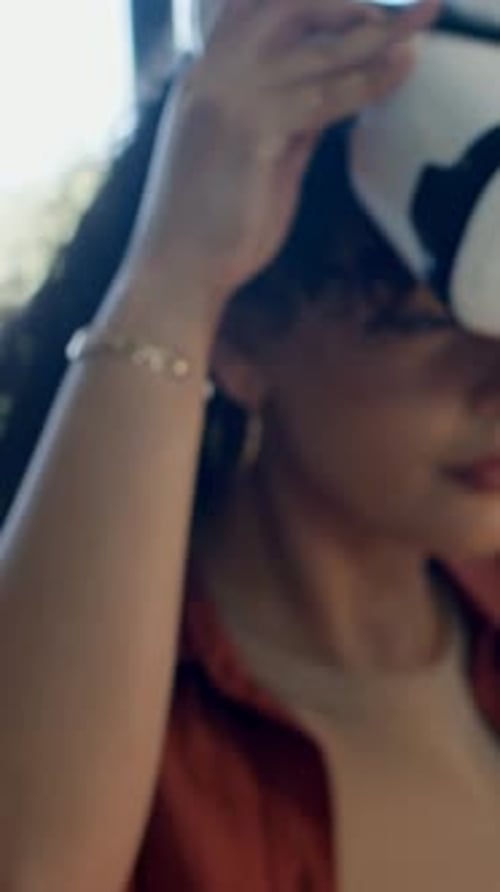 Vidéo verticale : amener une femme soulevant et alignant un casque VR blanc dans une pièce lumineuse, pour en tester l'ajustement
