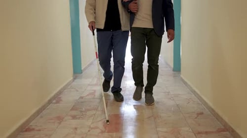 Junger Mann hilft Sehbehinderten beim Gehen