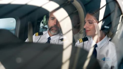 Experienced Male Instructor Teaching Young Female Pilot in Cockpit