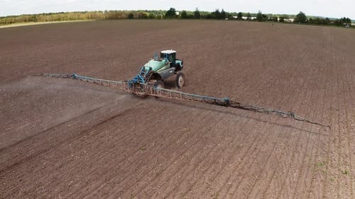 Tractor spraying chemical pesticides with sprayer on the large agricultural field