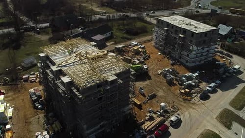 Construction Workers Installing Roof Trusses On Top Of An Unfinished Building. aerial orbit