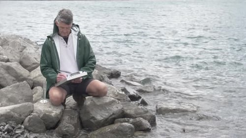 Man taking water sample on rocky shoreline