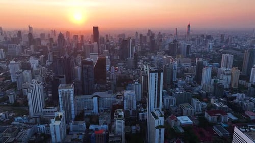 City skyline illuminated by a vibrant sunset casting shadows over buildings