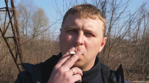 Portrait d'un homme adulte sérieux regardant la caméra et fumant une cigarette en plein air Concept de malsain