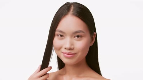 Smiling Woman Combs Long Hair on White Background