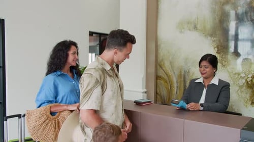 Man Paying by Card during Hotel Check In with Family at Reception