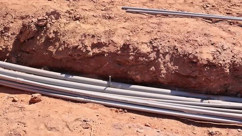 Construction Site Shows Freshly Laid Pipes in Trench in Rural Area