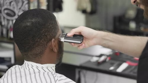 Barber Trimming Hair with Electric Razor in Shop