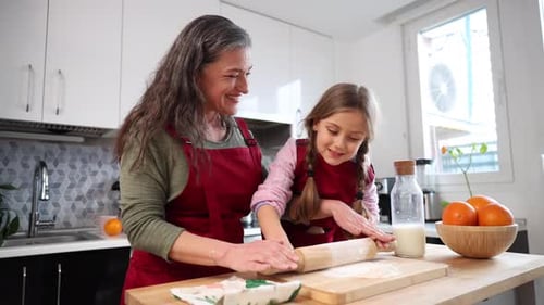 Grandmother and Granddaughter Rolling Dough Together in the Kitchen