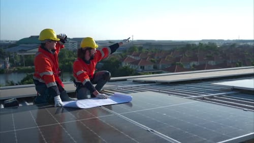 Engineer and technician working on the solar panel on the warehouse roof to inspect the solar panels