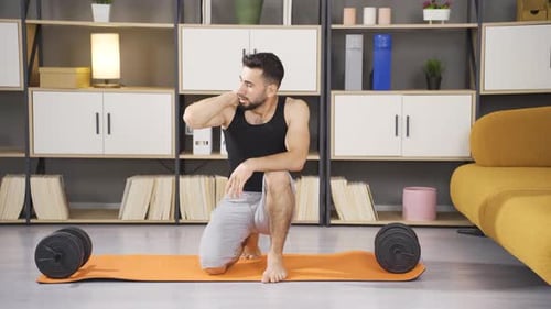Man Kneeling Beside Dumbbells on Yoga Mat