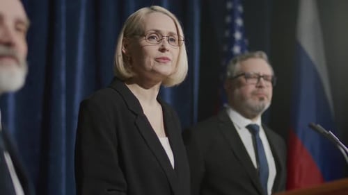 Adults Speak at a Formal Press Conference with Flags