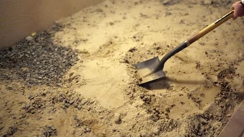 Man Shoveling Sand and Gravel Indoors