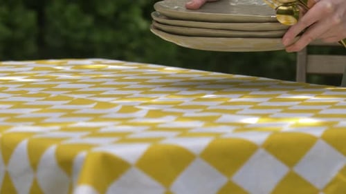 European girl places plates on tablecloth on table