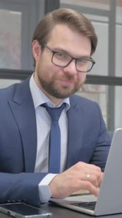 Thumbs Up by Young Businessman Looking at Camera in Office