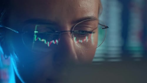 Trader Wearing Glasses arbeitet an einem Laptop-Bildschirm mit Börsencharts und Bitcoin BTC