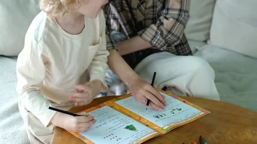 close-up mom helps her son do his schoolwork at home