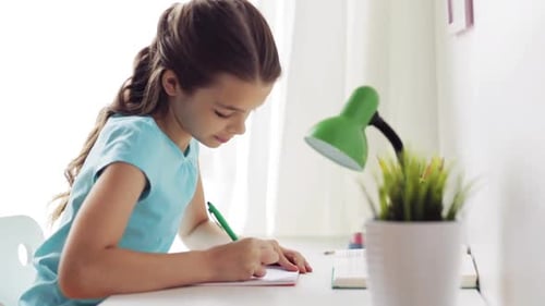 Girl writing in a notebook at a desk
