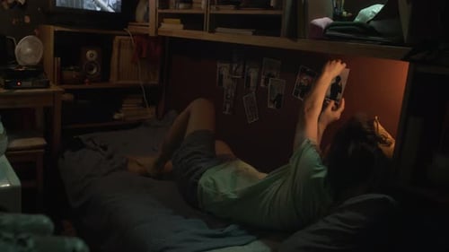 Young Adult Looking at Photographs in Bedroom at Night