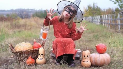 Girl in Witch Costume Poses with Pumpkins