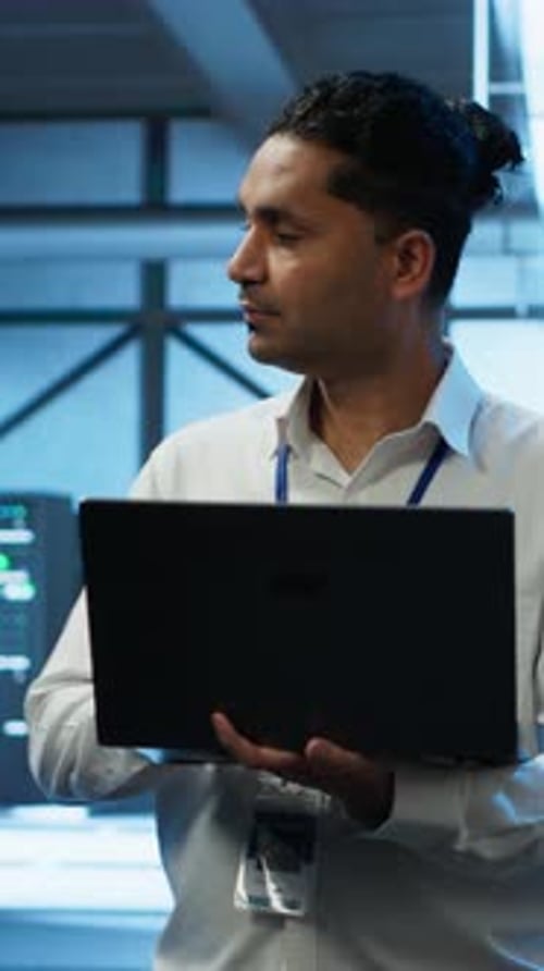Vertical Video Technician Using Laptop in Data Center Managing Servers