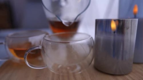 Tea Pouring into Clear Mug With Candles