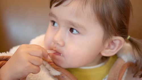 Adorable Child Eats Yogurt with a Spoon Indoors