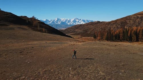 Hiker Walking in Rural Valley with Distant Mountains