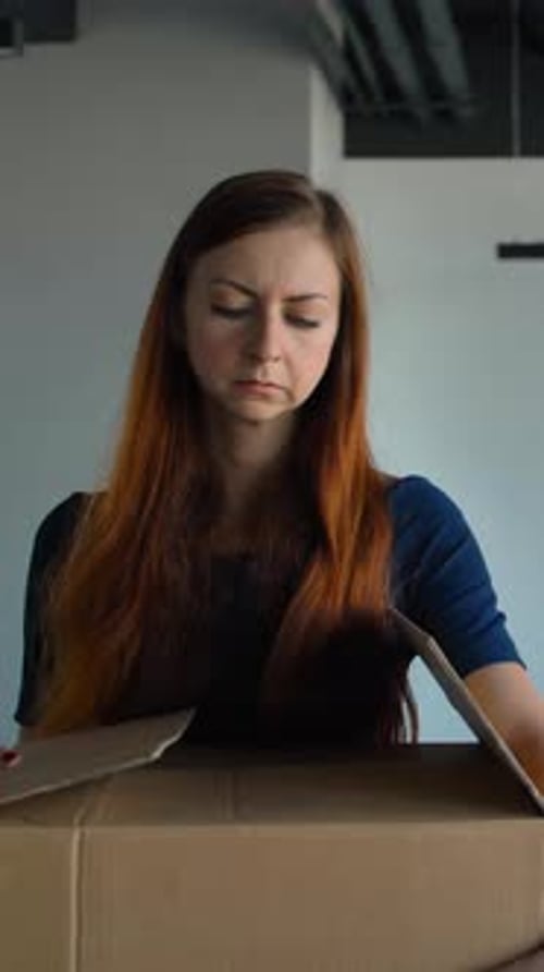 Vertical of Sad Employee Packing Her Belongings and Leaving the Office After Being Fired