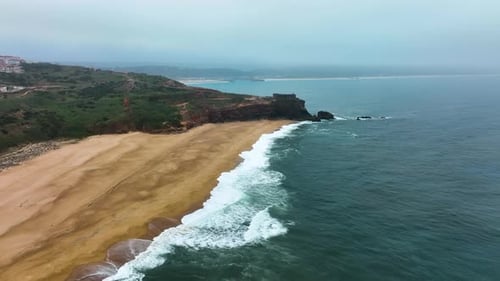 Coastal cliffs and beach under misty skies