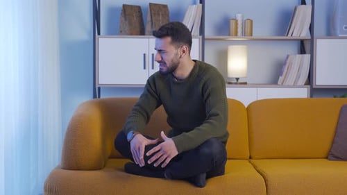 Sad young man crying at home at night.