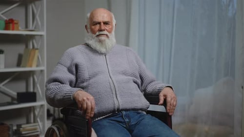 Senior Man with Beard Sitting in Wheelchair Indoors