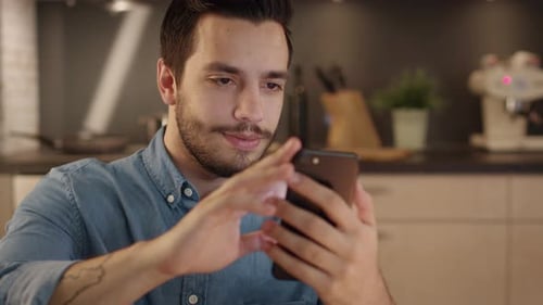Young Adult Using Smartphone in Modern Kitchen