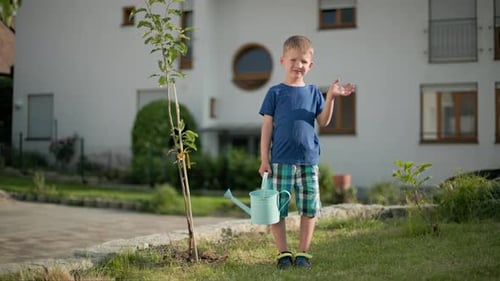 Boy With Watering Can Stands Near New Tree