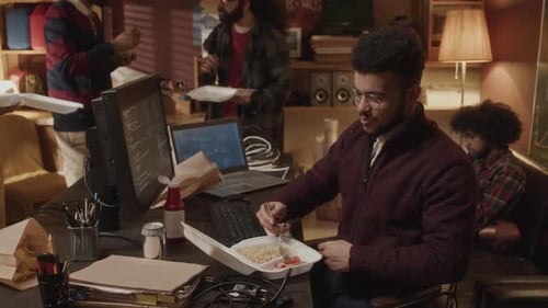 Young Biracial Programmer Having Lunch with Colleagues in Handmade Office