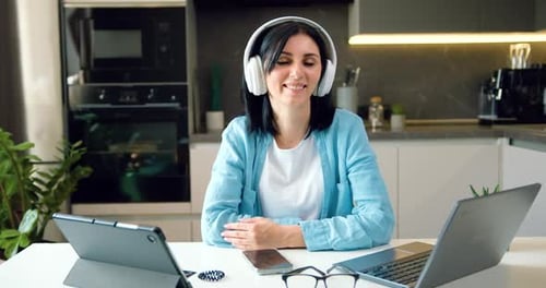 Retrato de una mujer autónoma sonriente con auriculares mirando a la cámara en casa. Fecha electrónica, evento de videollamada
