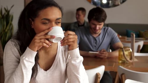 Dreamy Girl Savoring Coffee in a Cozy Cafe
