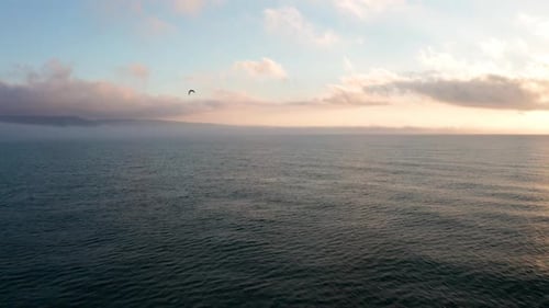 Ethereal Ocean View with Mist and Soft Sunset Clouds on Horizon