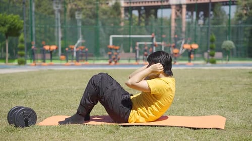 Un jeune homme qui fait des sit-ups à l'extérieur fait du sport et veut un corps en forme.