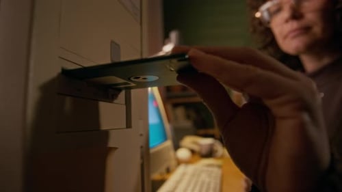 Benutzerin legt Diskette in das Laufwerk eines Retro-Computers ein