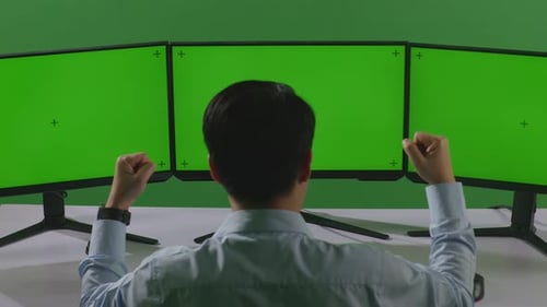Man Celebrating And Dancing While Working With Mock Up Multiple Computer Monitor In Green Screen