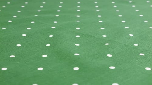 Top view of the viridian green with white polka dots cotton fabric rotated on the display case.